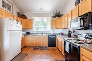 A kitchen with wooden cabinets, a white refrigerator, a black microwave, a stove, and a dishwasher.