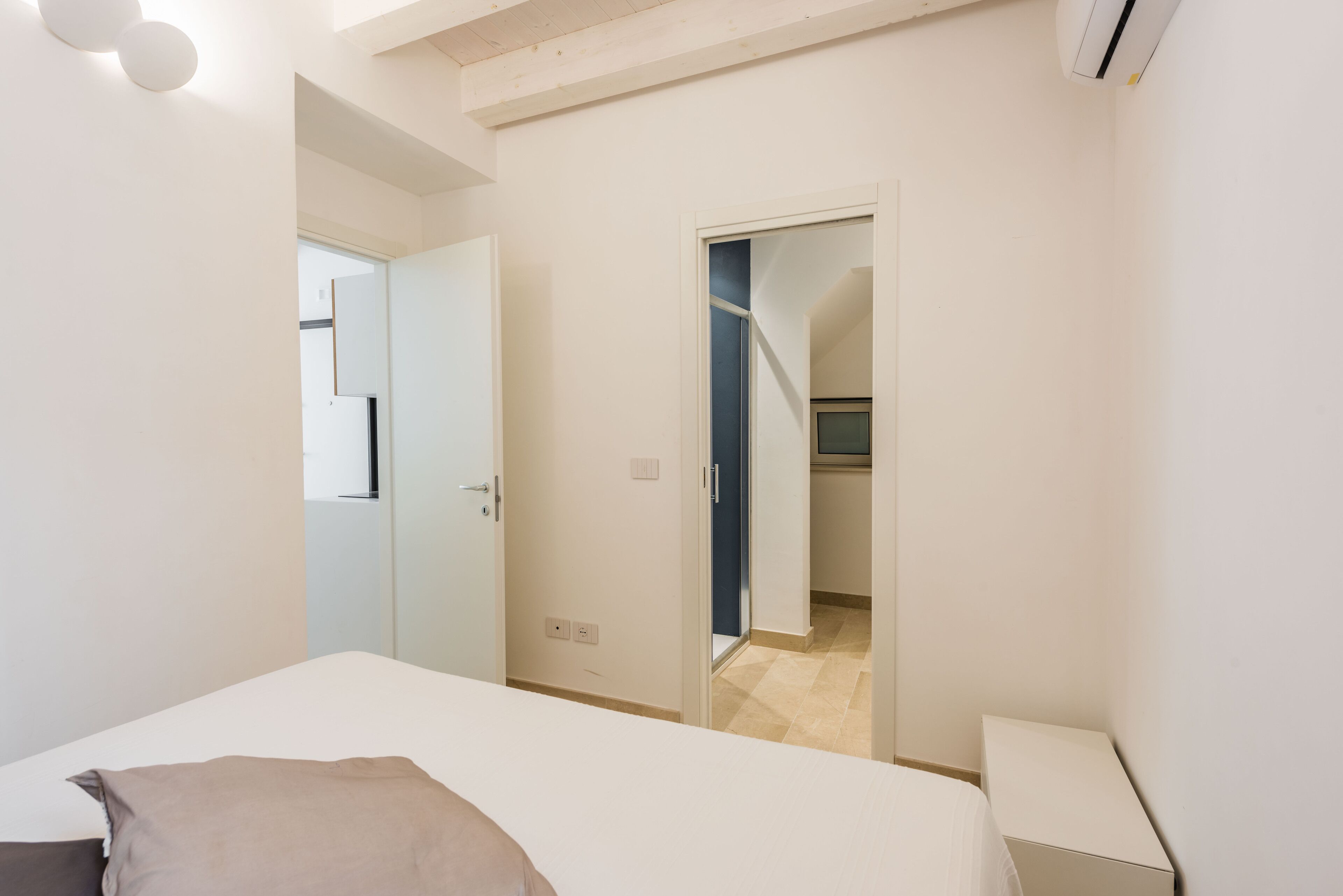 Quarto com cama, mesa de cabeceira e porta para um banheiro.