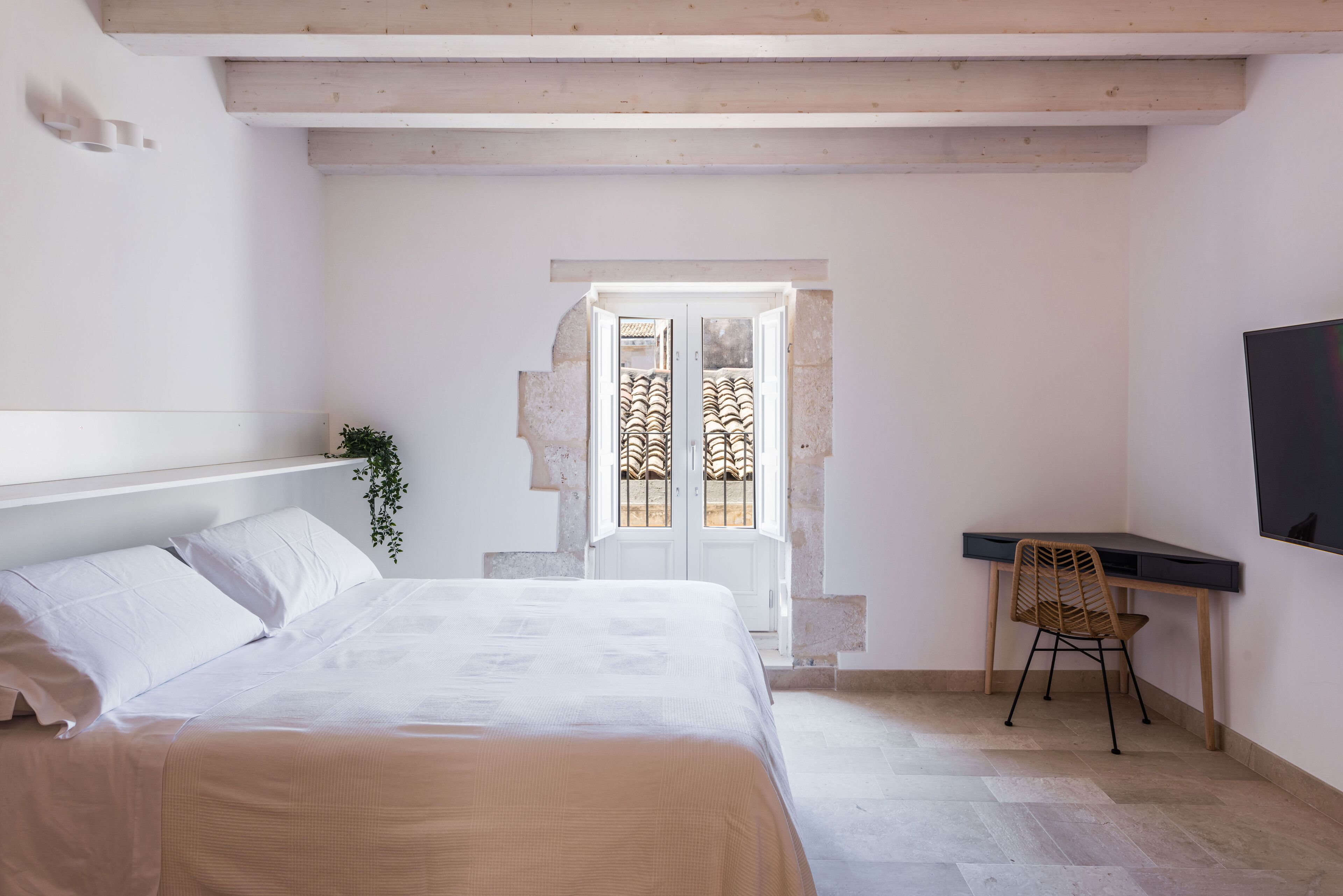 Een slaapkamer met een bed, een bureau en een stoel.