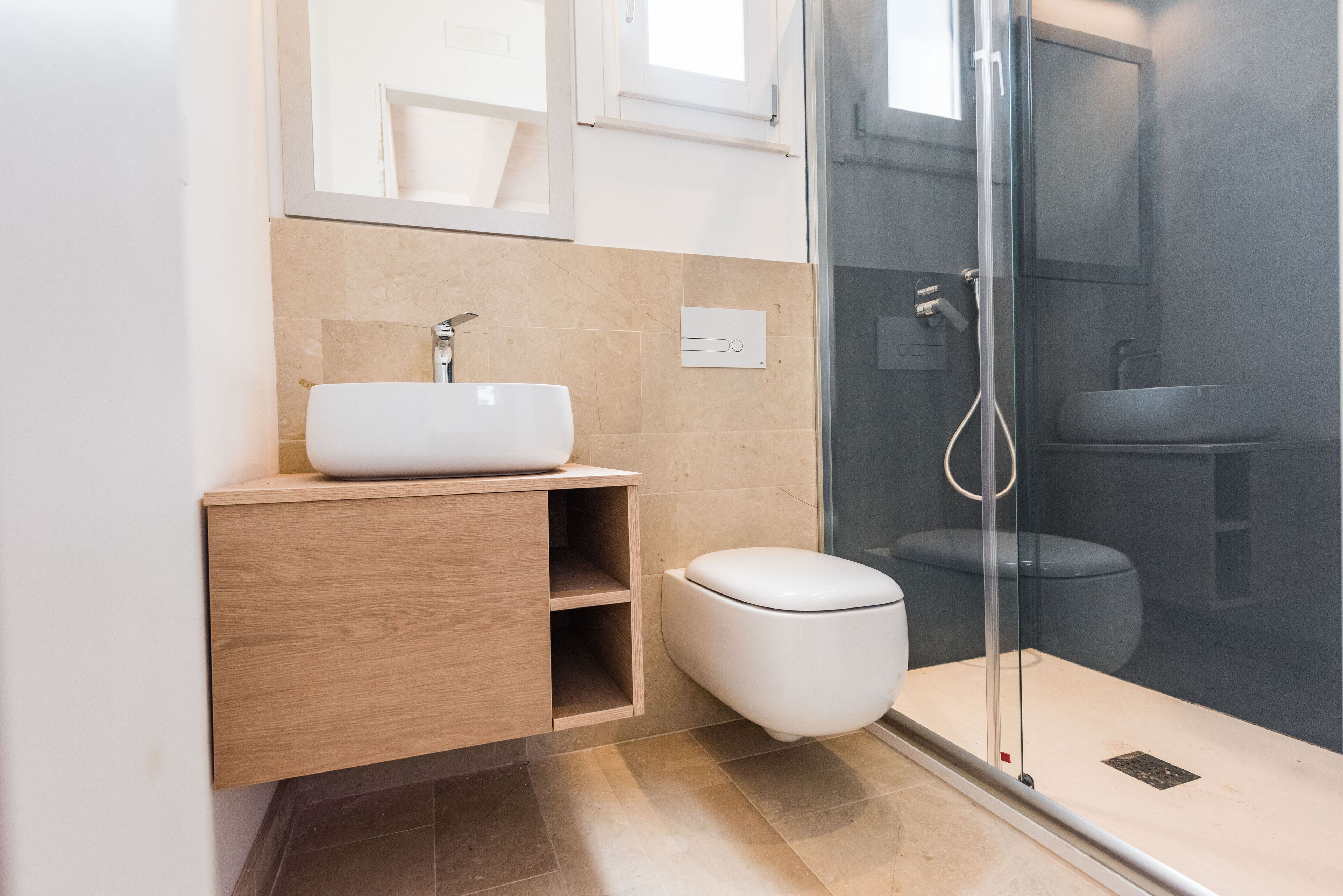 Ein modernes Badezimmer mit einer Duschkabine aus Glas, einem weißen Waschbecken und einem Holzbadezimmer-Möbel.