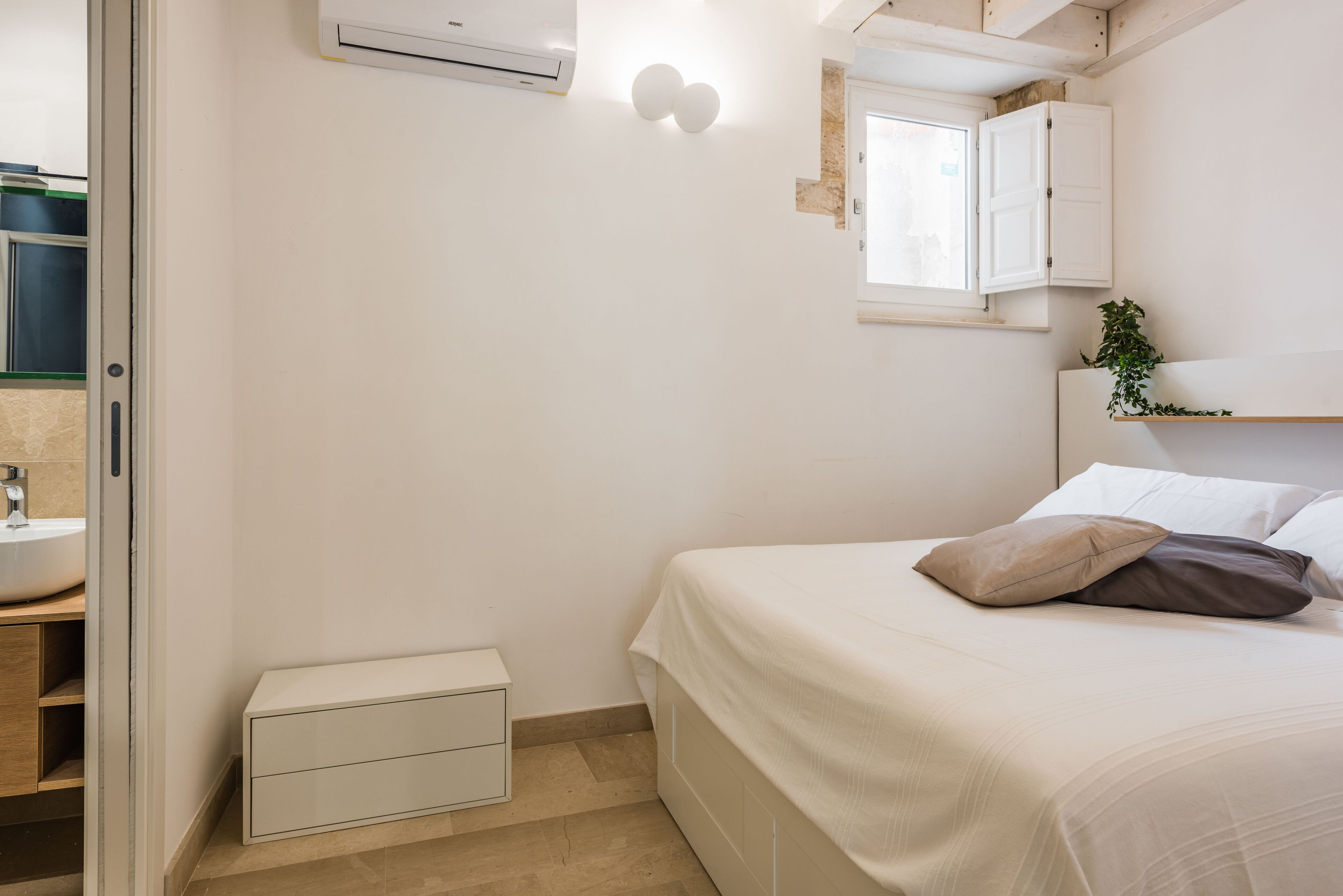 A bedroom with a bed, bedside table, and a small white cabinet.