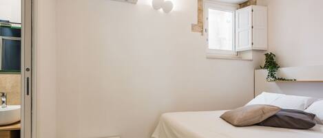 A bedroom with a bed, bedside table, and a small white cabinet.