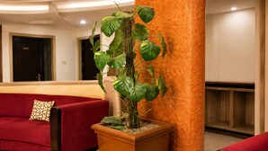 A lobby with a red sofa, a potted plant, and a checkered floor. - Hotel Europa Inn (Rajkot)