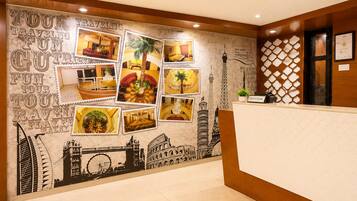 Zona de recepción de un hotel, con una pared decorada con fotografías de viajes y un mostrador de recepción.