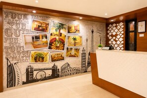 Un hall d'accueil d'hôtel avec un mur décoré de photographies sur le thème du voyage et un comptoir d'accueil.