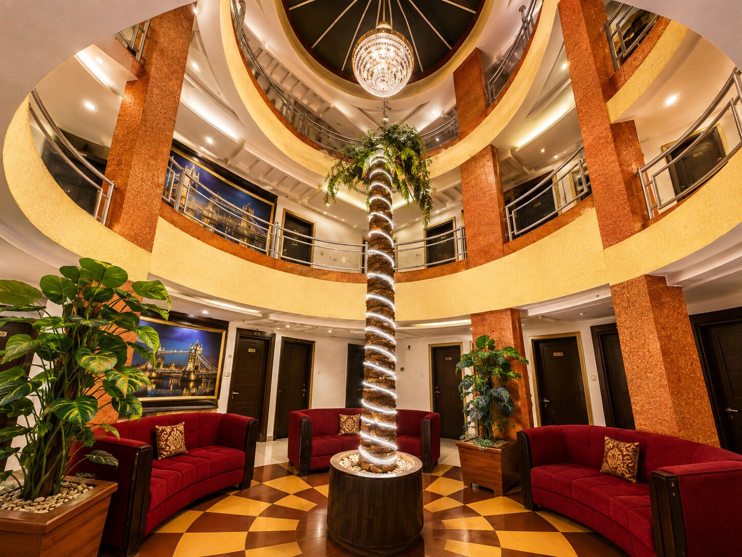 A multi-level hotel lobby with a central spiral staircase, red sofas, and potted plants.