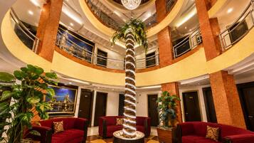 A multi-level hotel lobby with a central spiral staircase, red sofas, and potted plants.