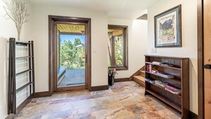 A hallway with a stone floor, a bookshelf, a framed picture, and a door leading to a balcony.