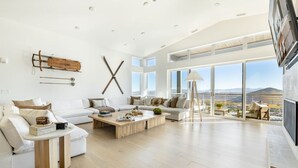 Ein geräumiges Wohnzimmer mit großem Fenster, einem weißen Sofa, einem Couchtisch und Blick auf die Berge.