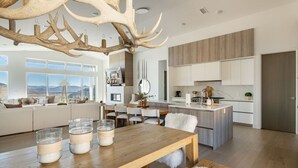 Eine moderne Küche mit wei ßen Schränken, einer Holztheke und einem großen Kronleuchter aus Hirschgeweihen.