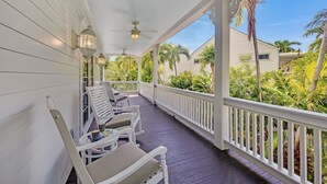 A covered porch with white railings, two white cushioned chairs, and a small table with a book. - **SIREN'S SERENADE @ THE ANNEX** Home & Pool + Last Key White Glove Service... (Key West)