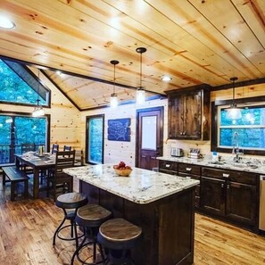 Un'ampia cucina con travi in legno, una grande isola con sgabelli e vista dalle finestre.