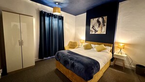Ein Hotelzimmer mit einem Bett, einem Kleiderschrank, einem Nachttisch mit Lampe und einem Bild an der Wand.