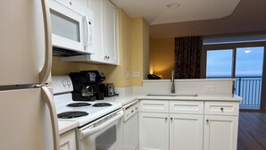 A compact kitchen with white cabinets, a stove, a microwave, a coffee maker, and a toaster. - RT-0703 Oceanfront 1-Bedroom Condo at Roxanne Towers, Myrtle Beach - Sleeps 6 (Myrtle Beach)
