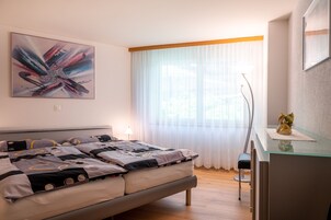 Un dormitorio moderno con cama, mesita de noche, lámpara y un cuadro abstracto grande en la pared.