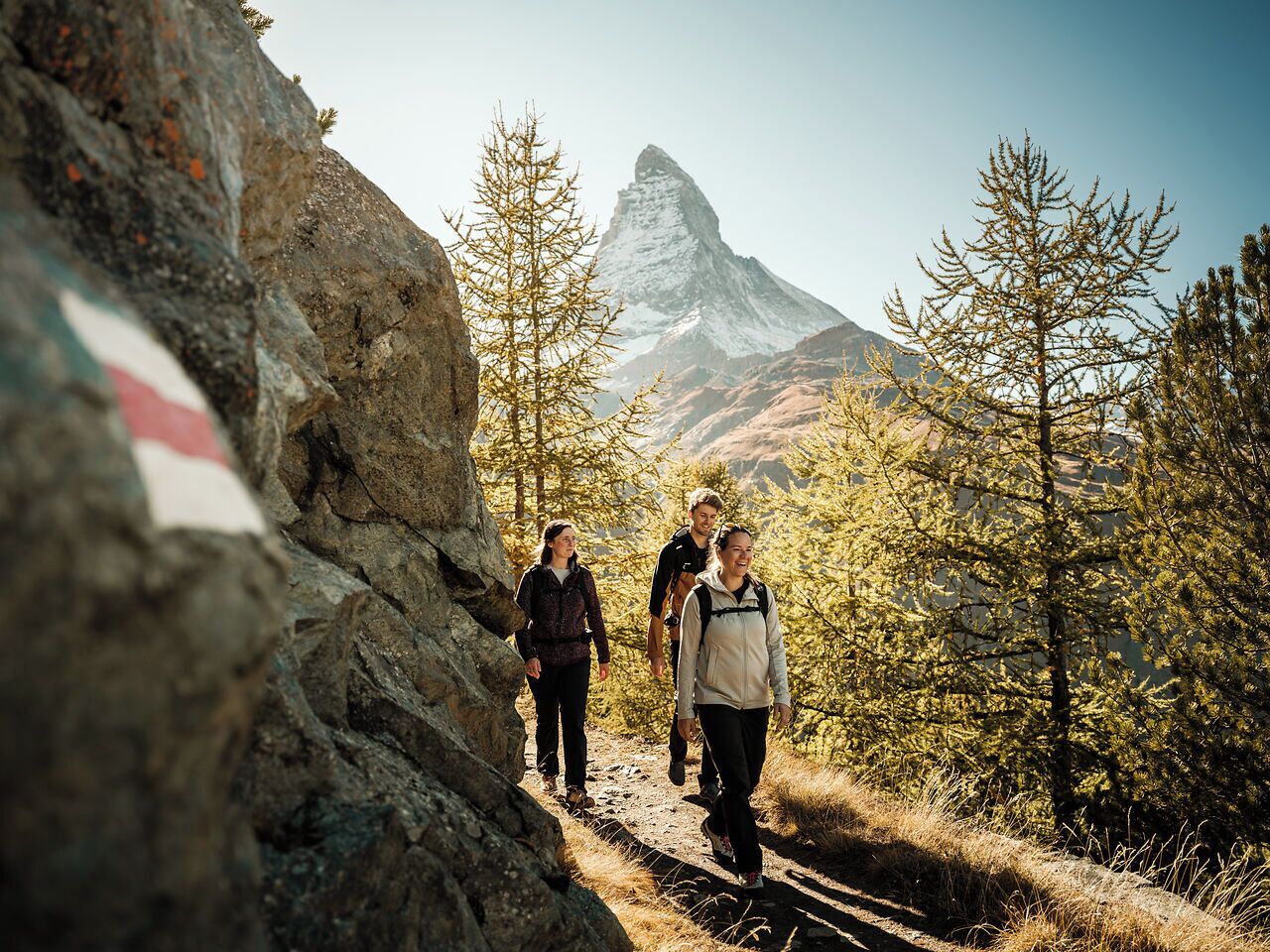 Un grupo de personas caminando por un sendero rocoso, con una montaña al fondo.