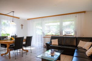 Una sala de estar con una mesa de comedor, un sofá de cuero negro y una mesa de centro de vidrio.