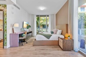 Une chambre d’hôtel moderne avec un lit, un bureau et de grandes fenêtres.