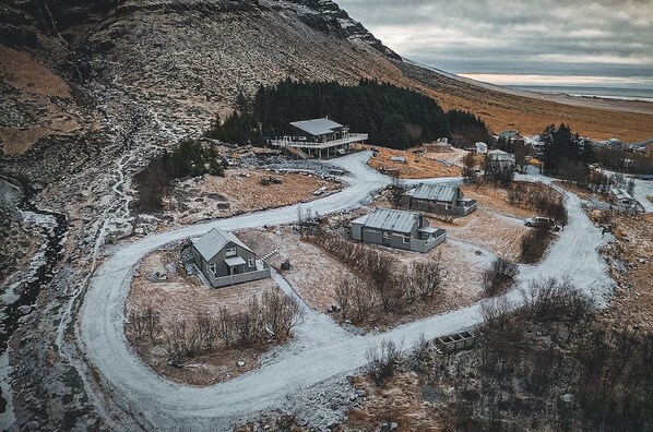 Un pueblo remoto y cubierto de nieve, con varias casas y un edificio grande, rodeado de montañas y un río.