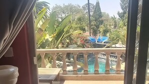 A view from a room to an outdoor area with a tiled floor, a railing, and a pool. - The Gallery Boutique Hotel (Harare)