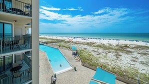 A hotel with a pool, beach view, and multiple balconies.