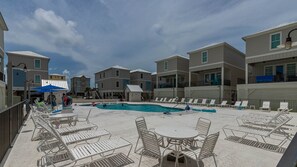 A pool area with lounge chairs and tables, surrounded by multi-story buildings with balconies. - West Side Cottages N - Your Gulf Shores Paradise Awaits (Gulf Shores)