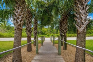A wooden boardwalk leading through a grove of palm trees. - West Side Cottages N - Your Gulf Shores Paradise Awaits (Gulf Shores)