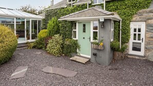 A cozy cottage with a small garden, a conservatory, and a stone wall.