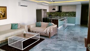 A modern living room with a sofa, coffee table, and a kitchen area with a bar.
