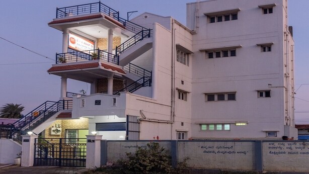 A multi-story building with a prominent staircase, a balcony, and a sign indicating a hotel. - JnJ Homestay (Chikkamagaluru)