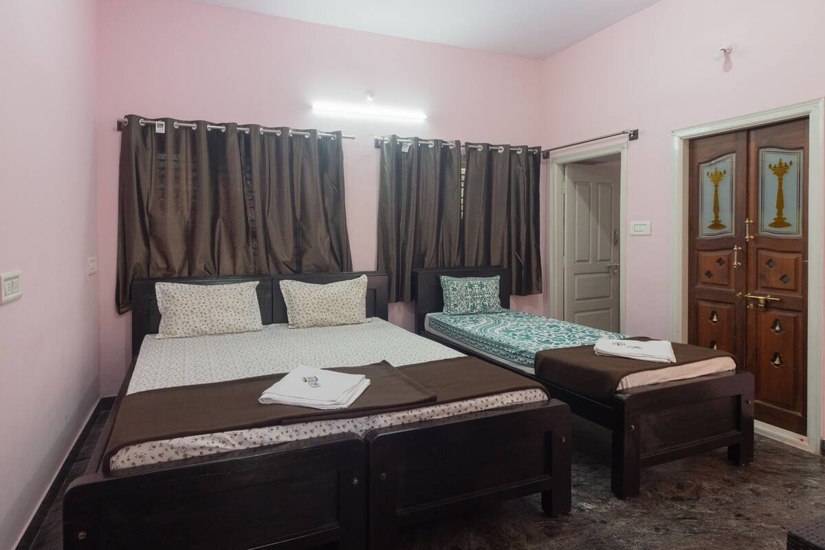 A bedroom with two beds, a ceiling fan, and a door with decorative elements.