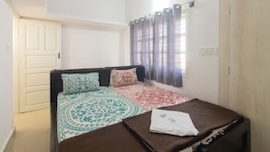 A bedroom with a bed, a wardrobe, a window with curtains, and a door. - JnJ Homestay (Chikkamagaluru)