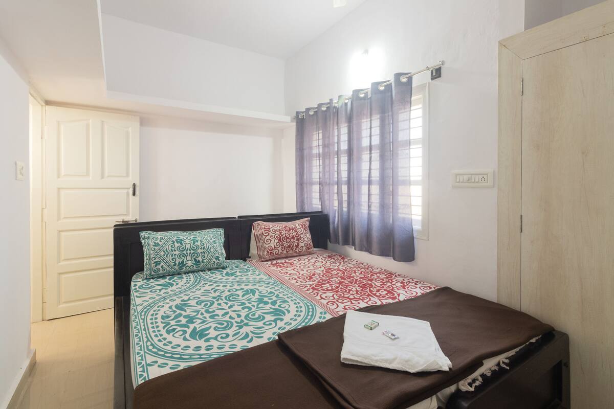 A bedroom with a bed, a wardrobe, a window with curtains, and a door.