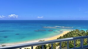 Uma praia com águas turquesa cristalinas, areal arenoso e coqueiros densos.
