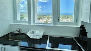 Cozinha com vista para uma cidade costeira através de três janelas em arco.
