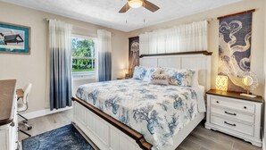 A bedroom with a bed, a nightstand, a desk, and a ceiling fan. - Seaduction Ami A 2 Bedroom Condo by RedAwning (Holmes Beach)