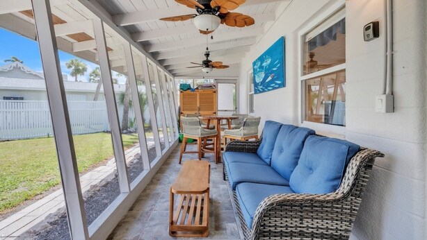 A covered patio area with wicker furniture, a ceiling fan, and a view of the backyard. - Seaduction Ami B 2 Bedroom Condo by RedAwning (Holmes Beach)