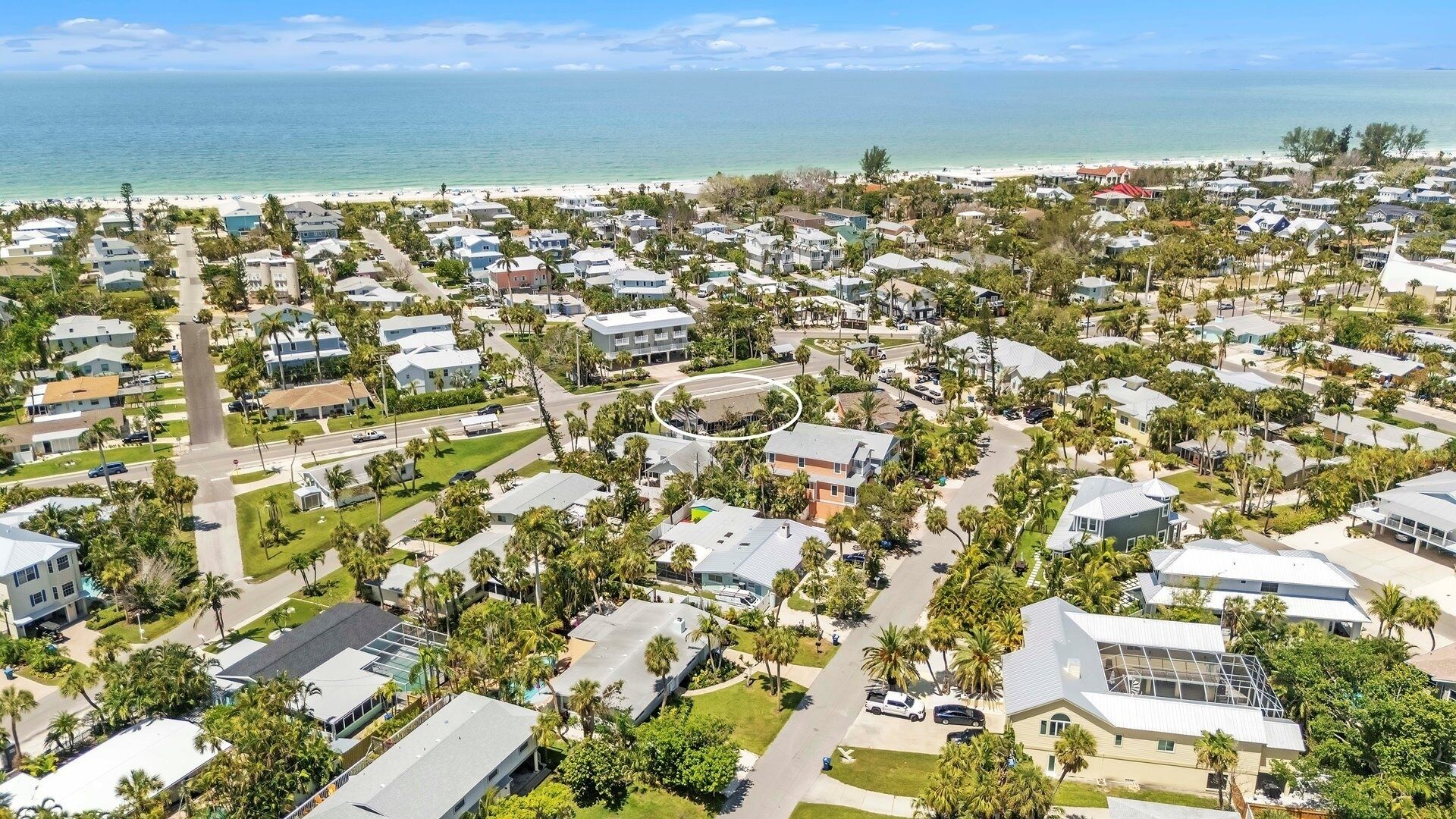 An aerial view of a coastal residential area with houses, roads, and a beach.