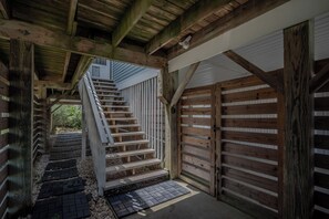 Una escalera de madera que conduce a una entrada con reja y barandilla de metal.