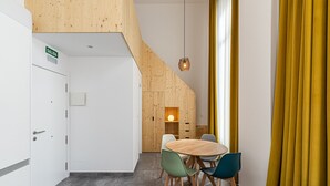 A modern interior with a wooden staircase, a dining area with a round table and chairs, and a yellow curtain.