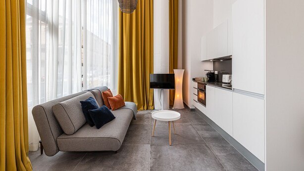 A modern living room with a sofa, a small round table, and a TV.