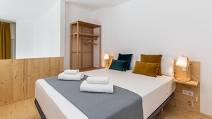 A modern hotel room with a large bed, a wooden wardrobe, and bedside lamps.