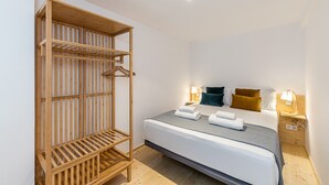 A bedroom with a bed, a wooden wardrobe, and bedside lamps. - Waou Modern Loft III Centre (Madrid)