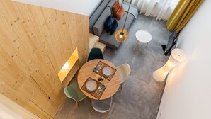 A modern dining area with a round wooden table, two chairs, and a sofa. - Waou Modern Loft III Centre (Madrid)