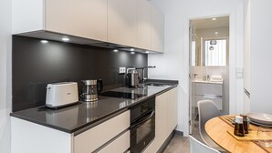 A modern kitchen with a black countertop, a coffee maker, a toaster, and a stove. - Waou Modern Loft III Centre (Madrid)