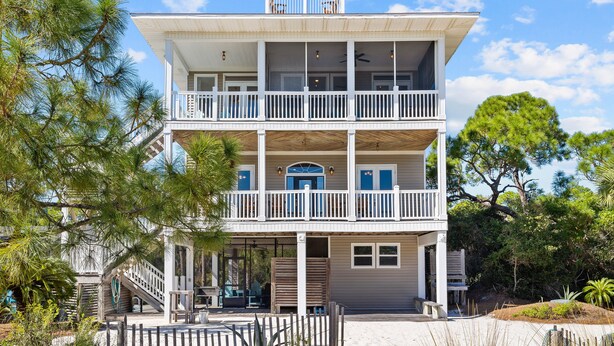 A two-story building with a balcony on the upper floor, surrounded by trees.