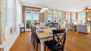 A spacious dining area with a wooden table set for six, surrounded by chairs.