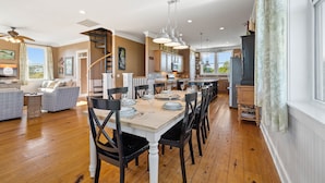 A spacious kitchen with a dining area, wooden flooring, and modern lighting fixtures.