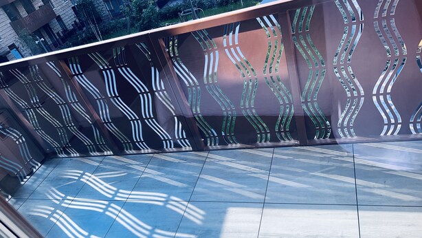 A modern balcony with a geometric metal railing and a tiled floor.