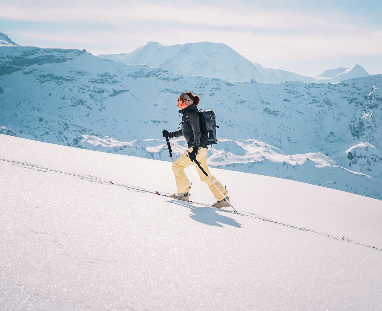 A person skiing on a snowy mountain with a clear sky.